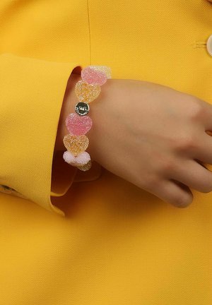 Färggad hjärtformad armband gjort av genomskinligt, strukturerat material med rosa, orange och klara sektioner, med en silverfärgad skivanhängande charm.