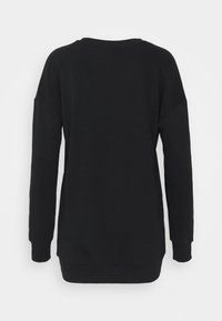 Felpa nera oversize con maniche lunghe, colletto e polsini a costine, morbida al tatto e con un orlo curvo sul retro.