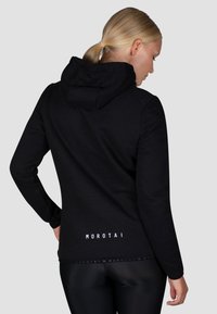 Schwarzer Hoodie aus weichem Stoff mit lässiger Passform, ausgestattet mit einer großen Kapuze und dem Markennamen "MOROTAI" in Weiß am hinteren Saum bedruckt.