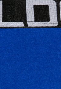 Blå stof med en glat tekstur, delt af et sort bånd med hvid skrift øverst.