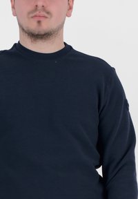 Felpa blu navy realizzata in tessuto testurizzato, con colletto a girocollo a costine e un piccolo logo sulla manica sinistra.