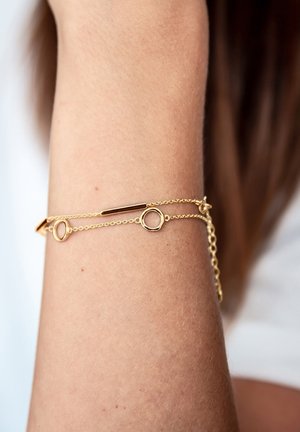 Bracciale in oro con maglie circolari e allungate, texture liscia, dal design minimalista e catena regolabile.