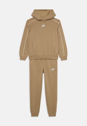 Ensemble en sweat à capuche et jogger marron en tissu doux, avec des bandes latérales blanches et un logo Nike blanc sur la poitrine et la jambe du pantalon.