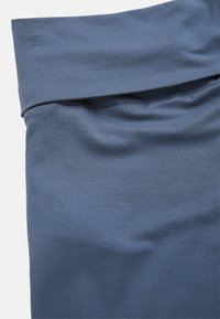 Sininen puuvillakangas, joka on aseteltu pehmeästi ja sileästi, with taitettu reuna ja lieviä ryppyjä, luoden rennon ilmeen.