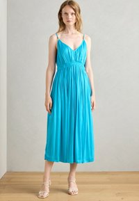 A sleeveless, mid-length dress in vibrant turquoise, featuring a pleated design, fitted waist, and decorative strap hardware.