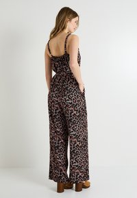Mono negro con un estampado de leopardo en tonos de rosa y rojo, con tirantes finos, un corpiño ajustado y pantalones de pierna ancha.