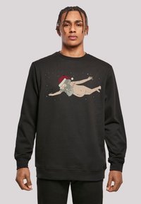 Svart sweatshirts med rund hals, som har en tecknad figur i tomteluva. Designen inkluderar en svävande karaktär mot en mörk bakgrund.