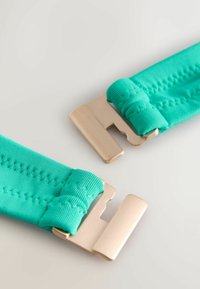 Turkizne elastične trakove z detajli šiva in zlato kovinskimi zaponkami. Trakovi so mehki in prožni, zasnovani za varno pripenjanje.