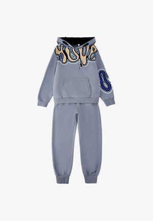 Completo per bambini composto da felpa con cappuccio e pantaloni azzurri con grafica astratta beige, nera e blu sul petto, sul cappuccio e sulla manica.