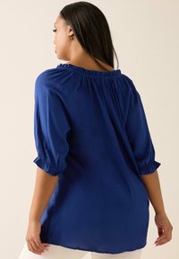 Mörkblå lätt blus med trekvarts puffärmar och rynkad hals, med en slät yta och lös passform.