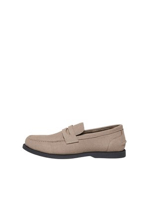 Lichtbeige suède loafer met zwarte zool en pennyriemdetail, getoond in zijaanzicht op witte achtergrond.