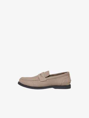Mocasín de ante beige claro con suela negra y detalle de correa para moneda, mostrado en perfil lateral sobre fondo blanco.