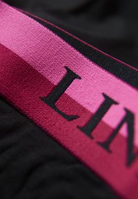 Schwarzer Stoff mit einem breiten rosa und burgunderfarbenen Band, das strukturierte Streifen und auffällige schwarze Buchstaben mit der Aufschrift "LIN" zeigt. Nahaufnahme, die den Detailreichtum betont.