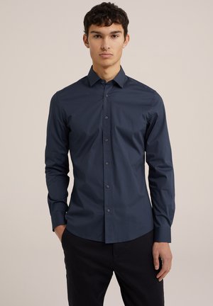 Marineblaue Langarmbluse aus glattem Stoff mit Button-Down-Kragen und abgerundetem Saum, die ein einfaches, maßgeschneidertes Design bietet.
