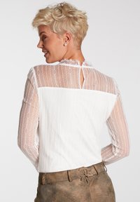 Weiße Bluse mit transparenten Spitzenärmeln im Diamantmuster und Mandarin-Kragen, einschließlich eines Rücken-Schlüsselloch-Ausschnitts und Knopfverschluss.