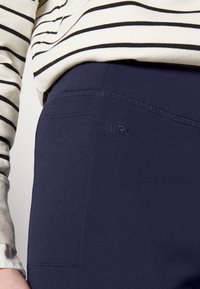 Marina leggings tillverkade av mjukt, elastiskt material, med en sydd söm och en LRL-logotyp på sidan, i kombination med en randig topp.