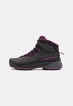 Zwarte wandelboot met roze accenten, voorzien van een hoge snit, een gestructureerd oppervlak, duurzame materialen en een robuuste zool voor grip.