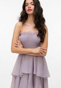 Lavendel strapless klänning med smockat liv, lagererad kjol och volangkrage. Tillverkad av lätt, texturerad tyg.