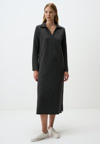 Graues, langärmliges Kleid aus weichem Stoff mit einem Kragen-Halsausschnitt und seitlichen Schlitzen, kombiniert mit weißen Sneakers. Einfaches, gerades Design.
