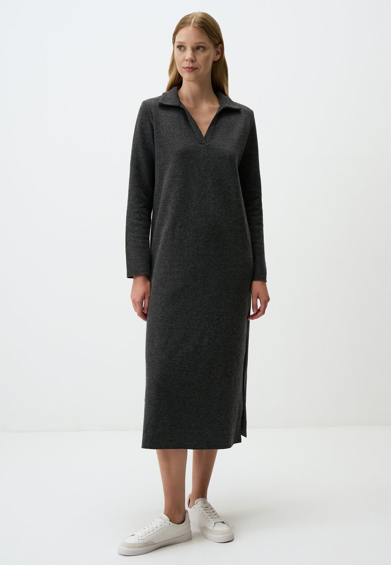 Graues, langärmliges Kleid aus weichem Stoff mit einem Kragen-Halsausschnitt und seitlichen Schlitzen, kombiniert mit weißen Sneakers. Einfaches, gerades Design.