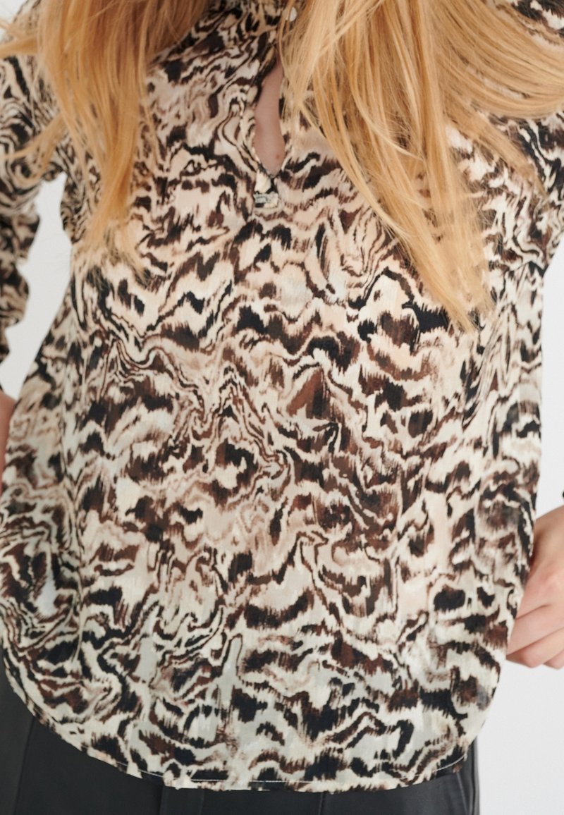 Blusa leggera e semitrasparente con un motivo astratto marrone e crema, presenta un collo a chiave e maniche lunghe.