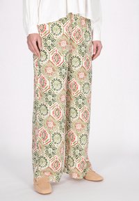 Pantaloni a gamba larga con un motivo floreale e geometrico, caratterizzati da colori verdi, rossi e crema. Tessuto morbido con una vestibilità rilassata.