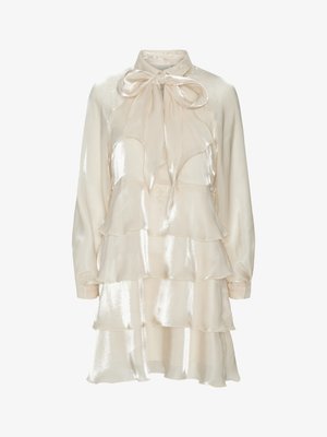 Cremefarbenes Satinlangarmkleid mit geschichteten Rüschen und einer großen Schleife am Kragen.