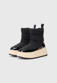 Zwarte enkelboots met een gewatteerde nylon bovenkant, lakleren accenten, een zijrits en een chunky beige platformzool. Structuur rubberen buitenzool.