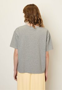 Hallide hallusleeve t-särk heledast puuvillast, millel on vaba lõige ja ümmargune kaelus, puhas äär ja minimalistlik, sile tekstuur.