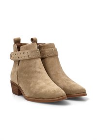 Botines de ante en color beige con punta afilada. Presentan una correa con tachuelas alrededor del tobillo y un tacón de madera bajo. Cierre lateral con cremallera.