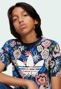 Navy floral t-shirt with pink, blue, and green patterns; features a white Adidas logo and round neckline; made from soft fabric.