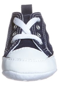 Námořnická plátěná teniska s bílou gumovou podrážkou, vybavená bílými tkaničkami a očky. Zaoblená špička a látkový poutko vzadu.