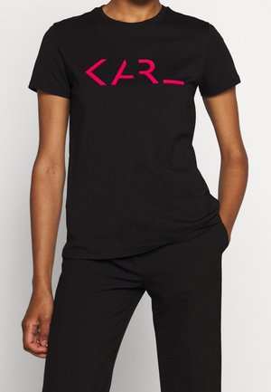 T-shirt en coton noir avec un design graphique rose vif et angulaire sur le devant. Col rond classique et manches courtes.