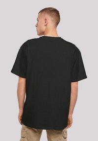 Black cotton t-shirt with a relaxed fit, short sleeves, and a crew neckline, shown from the back, featuring no visible graphics or details.