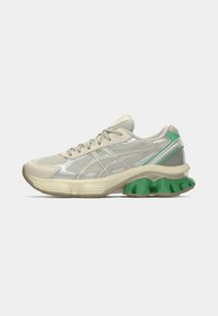 Light gray running shoe with mesh upper, silver accents, and green rubber outsole. Features padded collar and lacing for secure fit.
