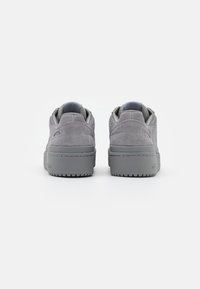Gray suede sneakers featuring a low-top design, thick rubber sole, and subtle stitching details. Back view shows cushioned collar and heel accents.