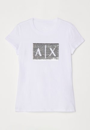 T-shirt bianca in cotone con maniche corte, dotata di una toppa rettangolare di paillettes argentate che mostra "A|X" in colori a contrasto.