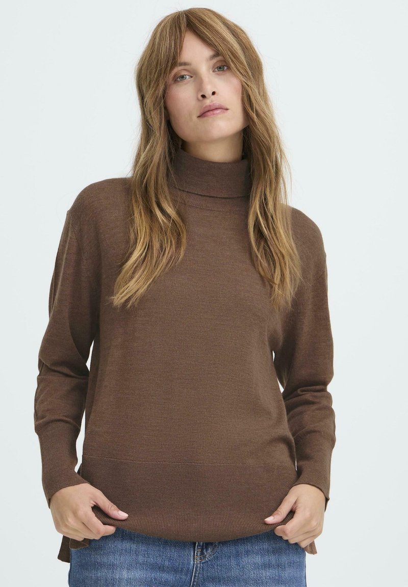 Brauner Strickpullover mit hohem Kragen, langen Ärmeln und geradem Saum. Weiche Textur und lockere Passform, kombiniert mit blauen Jeans.