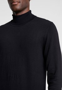 Schwarzer Rollkragenpullover aus weichem, feinem Strickstoff. Enganliegendes Design mit geripptem Kragen und Bündchen, minimalistischem Stil.