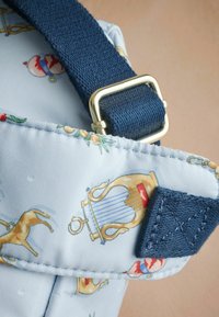 Blå mönstrad tygväska med musikaliska instrument och djur, med en marinblå rem och detaljer i guld. Texturerad sömnad synlig.