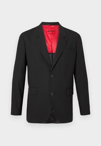 Blazer preto em tecido leve, com forro de cetim vermelho, dois botões na frente e dois bolsos laterais, além de um único bolso no peito.