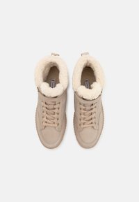 Baskets montantes beiges avec un doux col en fausse fourrure crème, dessus en nubuck texturé et design à lacets. Semelle en caoutchouc et boucle pour un enfilage facile.