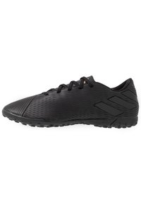 Botas de fútbol negras con una parte superior sintética texturizada, puntera curva, diseño de cordones y suela de caucho negra con patrones de agarre.