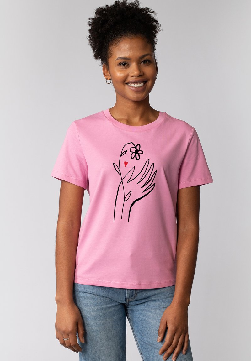 Rosa Baumwoll-T-Shirt mit einem schwarzen Linienstil-Design einer Hand mit einer Blume und einem Herz. Kurze Ärmel und ein klassischer Rundhalsausschnitt.