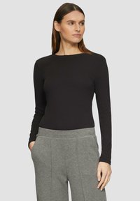 Zwarte longsleeve top van ribmateriaal, ronde halslijn, gecombineerd met grijze, wijde broeken met zijzakken en een gestructureerd ontwerp.