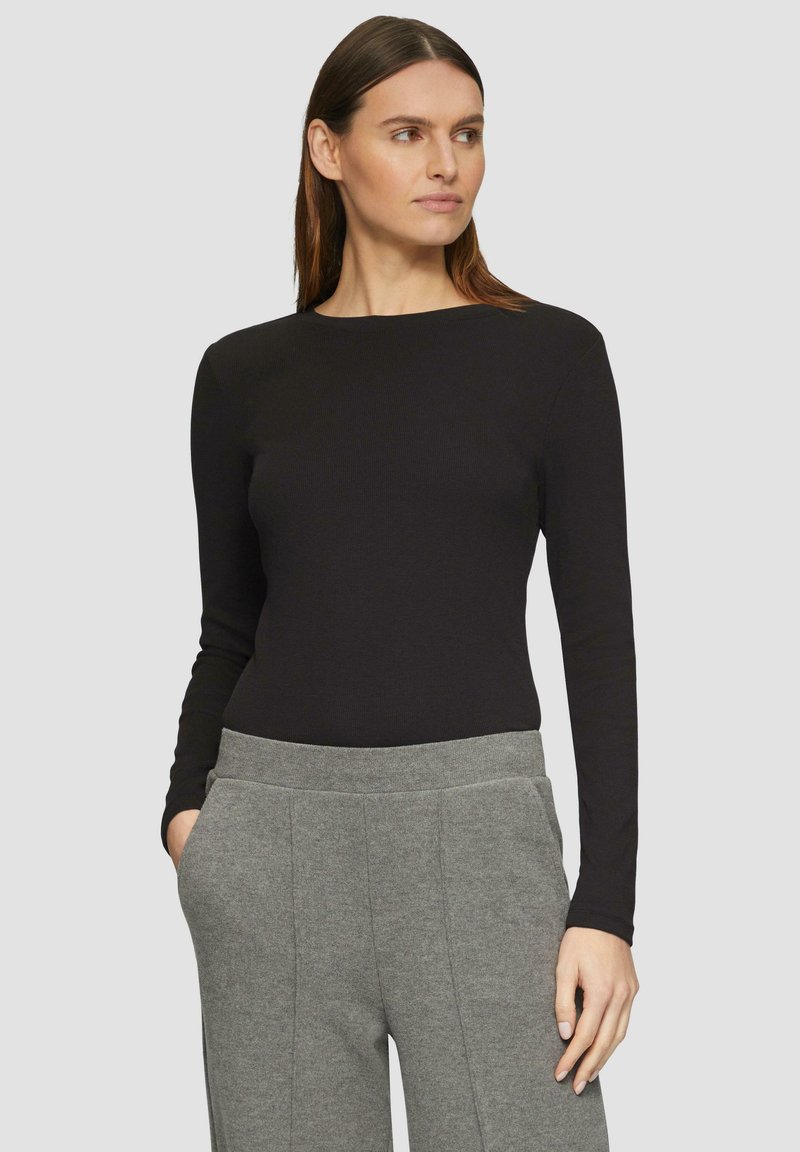 Zwarte longsleeve top van ribmateriaal, ronde halslijn, gecombineerd met grijze, wijde broeken met zijzakken en een gestructureerd ontwerp.