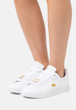 Białe skórzane sneakersy z złotymi akcentami, z wiązanym zapięciem, teksturowaną powierzchnią oraz detalem logo po boku i na języku.
