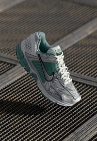 Nike trkačka cipela s prozračnim mrežastim gornjim dijelom u bijeloj boji s tirkiznim akcentima, crnim swoosh logotipom i podstavljenim ovratnikom za udobnost.
