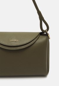 Borsa a tracolla in pelle verde oliva con finitura textured, chiusura a patta arrotondata e logo dorato. Include una tracolla removibile e bordi lisci.