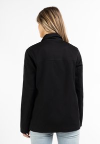 Černá bavlněná bunda s límcem, dlouhými rukávy a rovného střihu. Hladký povrch a minimalistický design bez viditelného kovového příslušenství.
